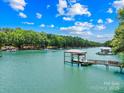 Stunning waterfront view featuring a private covered dock with serene water and lush trees at 228 Wildwood Cove Dr, Mooresville, NC 28117