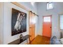 Stylish foyer featuring a sliding barn door, a unique horse portrait, and a vibrant orange front door at 416 E 18Th St, Charlotte, NC 28206