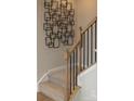 Carpeted stairs with wood railing and black iron balusters with modern wall decor above at 7216 Hodges Meadow Ln, Charlotte, NC 28213
