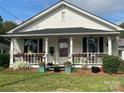 Charming white cottage with a covered porch adorned with flowers and seating creates a welcoming curb appeal at 1001 N Cannon Blvd, Kannapolis, NC 28083