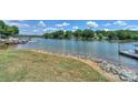 Scenic waterfront featuring a grassy shoreline reinforced with rocks, a calm lake, and boat docks under a sunny sky at 107 Pier 33 Dr # 103, Mooresville, NC 28117