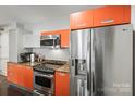 Modern kitchen featuring stainless steel appliances, orange cabinetry, and granite countertops at 1133 Metropolitan Ave # 318, Charlotte, NC 28204