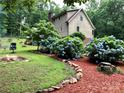 Lush backyard features a fire pit, blue hydrangea bushes, and manicured landscaping at 1496 Givens St, Hickory, NC 28602