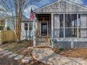 Charming screened porch entrance with a classic American flag, stone pathway, and tidy landscaping at 5300 Buckingham Dr, Charlotte, NC 28209