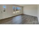 Empty living room with wood-look floors, fresh white walls, and ample natural light from the large front window at 8103 Idlewild Rd, Indian Trail, NC 28079