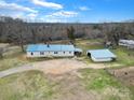 Aerial view of home with blue roof and detached garage surrounded by trees and open land at 836 Love Rd, Blackstock, SC 29014