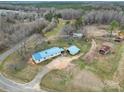 Overhead view of a home with a blue roof, outbuildings, and an expansive wooded and open landscape at 836 Love Rd, Blackstock, SC 29014