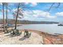 Lake side backyard with comfortable green Adirondack chairs on a white stone beach at 8513 Loxton Cir, Charlotte, NC 28214