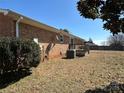 Backyard view showcasing the brick exterior of the house and a small wooden deck, bordered by mature shrubs and a lawn at 95 Icard Ridge Road Ext, Granite Falls, NC 28630