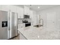 Open kitchen featuring stainless steel appliances, white cabinetry, and granite countertops on the center island at 114 Ciara Pl # E, Mooresville, NC 28117