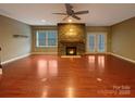 Bright living room featuring a stone fireplace, ceiling fan, and hardwood floors at 13217 Reunion St, Charlotte, NC 28278