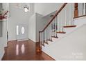 Bright foyer with hardwood floors, staircase with white spindles and wood railing, and a front door with glass detailing at 15323 Prescott Hill Ave, Charlotte, NC 28277