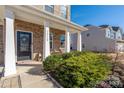 Inviting front porch with brick facade, white columns and attractive landscaping at 16110 Foreleigh Rd, Huntersville, NC 28078
