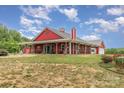 Charming red farmhouse with wraparound porch and well-manicured lawn at 223 Scottish Dr, Mooresville, NC 28115