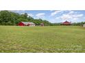 Scenic view of red farmhouse and barns set on rolling green hills at 223 Scottish Dr, Mooresville, NC 28115