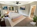 Stylishly staged main bedroom with neutral colors and a view to the outdoors at 2702 Occaneechi Ct, Waxhaw, NC 28173