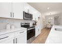 Close-up of kitchen with stainless steel oven, white cabinets, and view of the dining area at 4811 Victoria Ave, Charlotte, NC 28269