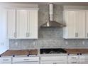 Modern kitchen featuring white cabinets, stainless steel range hood, and stylish backsplash at 13308 Chopin Ridge Rd, Huntersville, NC 28078