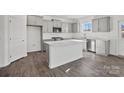 A kitchen with gray cabinets, stainless steel appliances, a white island, and light wood floors at 13744 Roderick Dr # 173, Huntersville, NC 28078