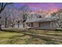 Cozy home with a large front yard and attached two-car garage, illuminated by a vibrant sunset at 15905 Sunset Dr, Huntersville, NC 28078