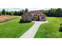 A charming home with a large driveway and lush green lawn is constructed of stone and brick at 1974 Glen Manor Ct, Lincolnton, NC 28092