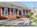 Welcoming brick home entrance with black shutters, classic black door, and well-maintained landscaping at 212 Glen Eagles W Rd, Statesville, NC 28625