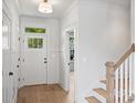 Bright foyer with hardwood floors, white walls, a wooden staircase, and a door with transom window at 12243 Monteith Grove Dr, Huntersville, NC 28078