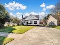 Wide shot of a traditional home with a long driveway and well-kept lawn, under a bright blue sky at 4540 Hounds Run Dr, Matthews, NC 28105