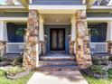 Inviting front porch with stone columns, decorative railings, and a beautifully crafted front door with sidelights at 8002 Pemswood St, Charlotte, NC 28277