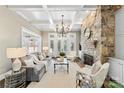 Comfortable living room featuring a stone fireplace, coffered ceiling, and ample natural light from large windows at 8002 Pemswood St, Charlotte, NC 28277