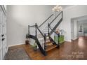 Inviting home foyer featuring hardwood floors, staircase with black railing, and chandelier lighting at 9334 Hunting Ct, Matthews, NC 28105