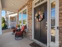 Welcoming front porch with chairs, a table with flowers, and a charming wreath on the front door at 9611 Rayneridge Dr, Huntersville, NC 28078