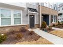 Close up of the home's exterior entrance featuring neutral siding, dark brick, and minimal plantings at 110 Wesser St, Davidson, NC 28036