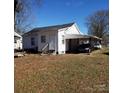 View of the rear of a white home with carport, wooden steps and yard at 116 Nella St, Chester, SC 29706