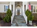 Elegant front entrance with stone steps, lush greenery, and decorative pillars at 12860 Westmoreland Farm Rd, Davidson, NC 28036