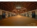 Interior view of horse barn with wooden stalls, beamed ceiling, and dirt floor running down the middle of the barn at 2137 Old Latter Rd, Newton, NC 28658