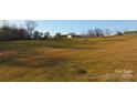 Large land plot with grassy field featuring a couple buildings and horses grazing under a clear blue sky on a sunny day at 2137 Old Latter Rd, Newton, NC 28658