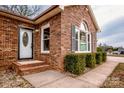 Close-up of the front entrance, featuring a storm door, brick facade, and manicured landscaping at 342 Monticello Rd, Statesville, NC 28625