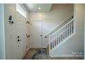 Bright foyer with light floors, white walls, coat hooks, and staircase with white railing at 4022 Carl Parmer Dr, Harrisburg, NC 28075