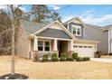 View of charming home with stone accents, covered front porch, 2-car garage, and manicured landscaping at 488 Sandbar Pt, Clover, SC 29710