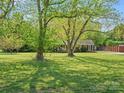 Spacious front lawn with mature trees surrounding a cozy one-story brick home and covered front porch at 6349 Lebanon Rd, Mint Hill, NC 28227