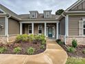 Inviting front entrance with a well-manicured garden, stone accents, and a covered porch at 10521 Ardley Manor Dr, Mint Hill, NC 28227