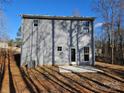A view of the back of the house featuring a gray siding, a small patio, and a wooded backdrop at 112 Brook Creek Dr, Troutman, NC 28166
