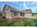 Side view of a gray brick home displaying the architectural details and professional landscaping at 1202 Louise Ln, Albemarle, NC 28001