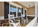 Inviting front porch featuring white rocking chairs, decorative pillows, and a welcoming wreath on the front door at 136 Kingston Dr, Locust, NC 28097