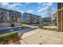 Street view of cozy townhomes featuring stone accents, gray siding, and attached garages at 1932 Catkin Ln, Charlotte, NC 28205