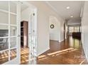 Hallway with rich hardwood flooring and arched openings, leading to an office with French doors and a view of the living area at 241 Catoctin Rd, Rock Hill, SC 29732