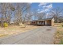 Brick home with a covered front porch, rocking chairs, American flag, and long driveway at 437 Valley St, Stanley, NC 28164