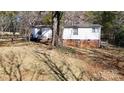 View of the backyard featuring a well-maintained lawn, mature trees, and partial fencing at 5124 Gates Dr, Denver, NC 28037
