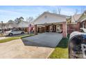 Exterior view of a brick house featuring a carport and well-maintained lawn with American flags displayed at 7004 Owens Ct # B, Lowell, NC 28098